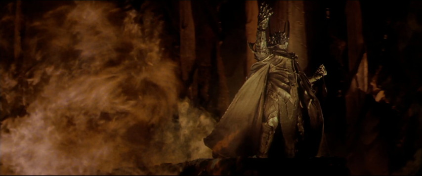 An image from the movie "The Lord Of The Rings: The Fellowship Of The Ring". Sauron, a menacing figure clad in black armor, surrounded by flames.