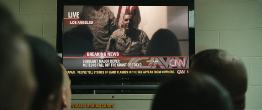 An image from the move Battle Los Angeles. Soldiers watch a televsision showing breaking news of an alien invasion.